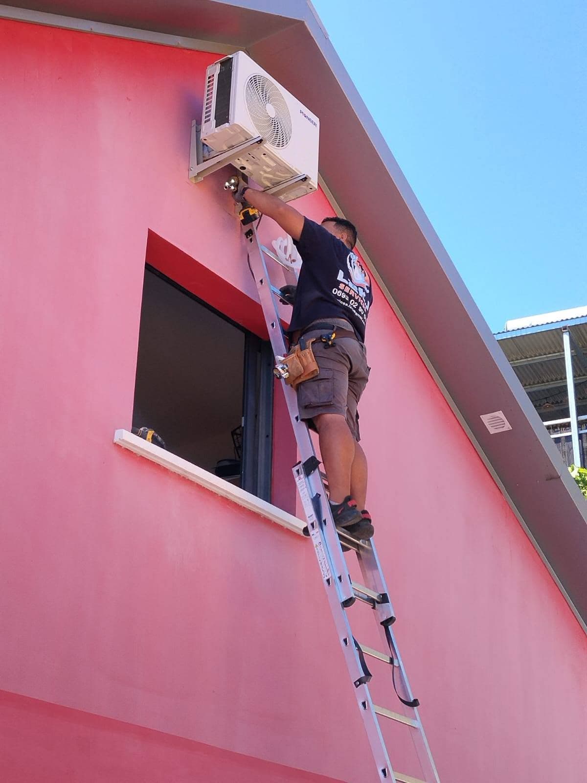 Technicien installant une unité extérieure de climatisation en hauteur